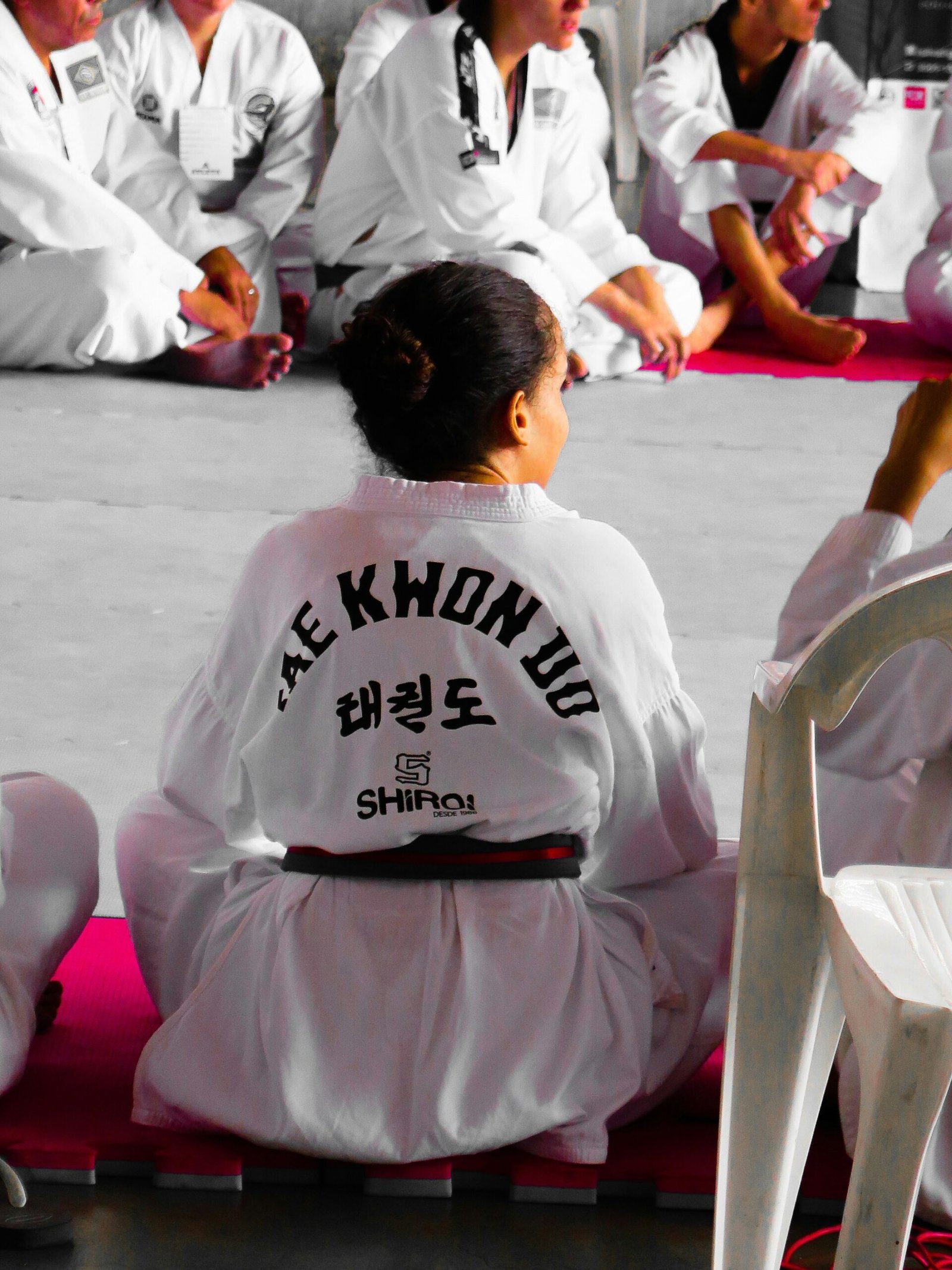 Young female Taekwon-Do student sat down on the mat