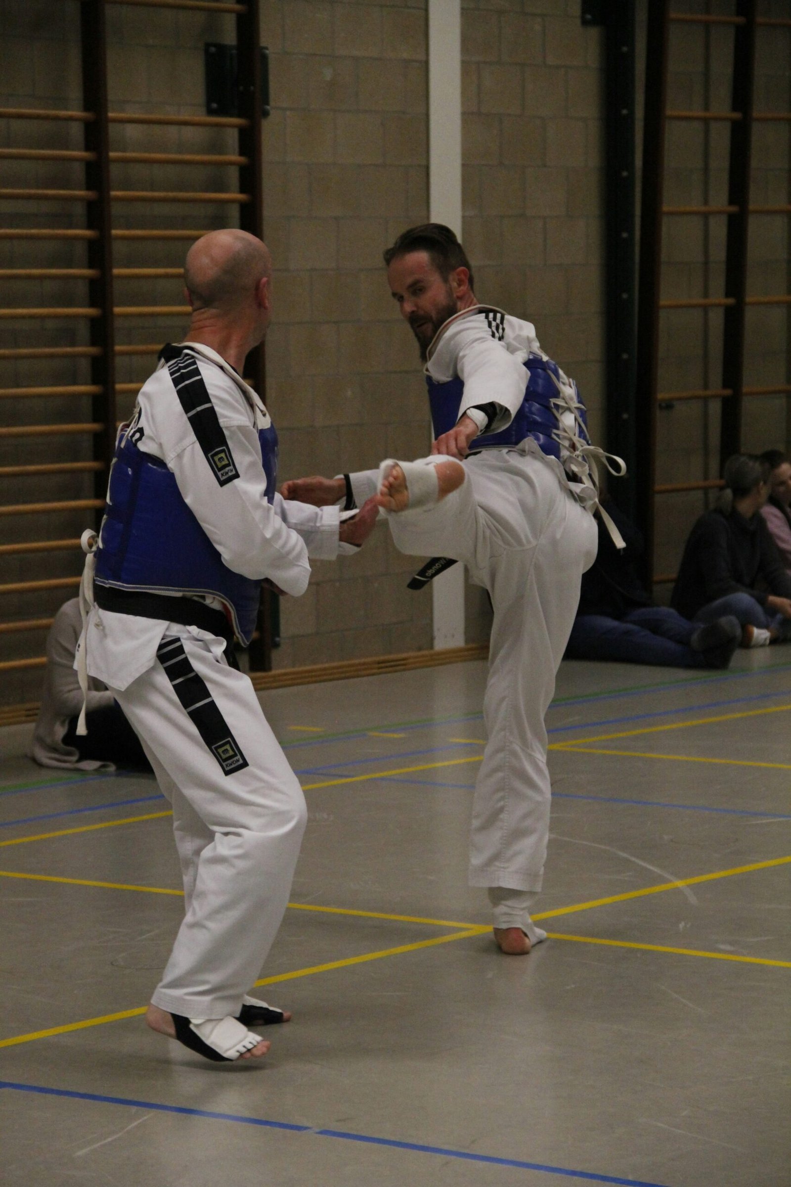 Two men sparring in a well lit hall.